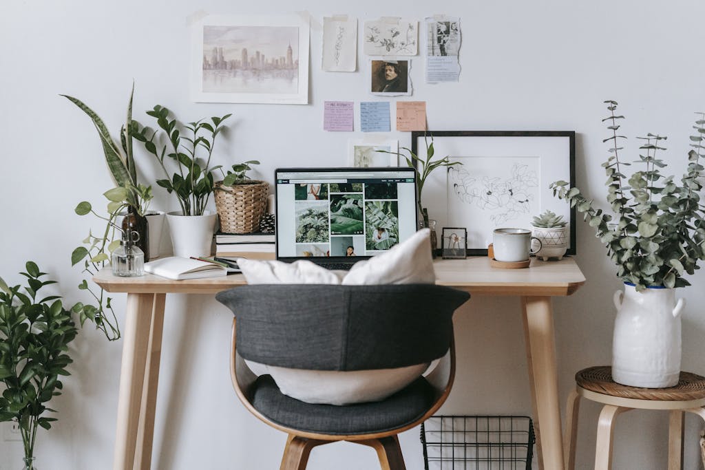 Comfortable workplace with laptop and green plants at table